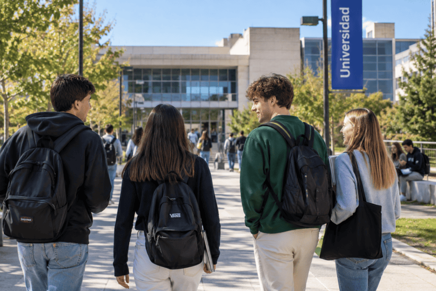 Estudiantes universitarios caminando por el campus de una universidad con mochilas y libros